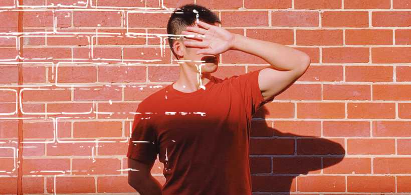 un hombre con una camisa roja tapandose la cara con su mano