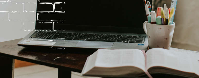 una computadora y una biblia encima de una mesa