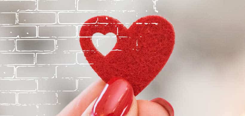 una mujer aguantando un corazón de papel que contiene otro corazón más pequeño adentro de el