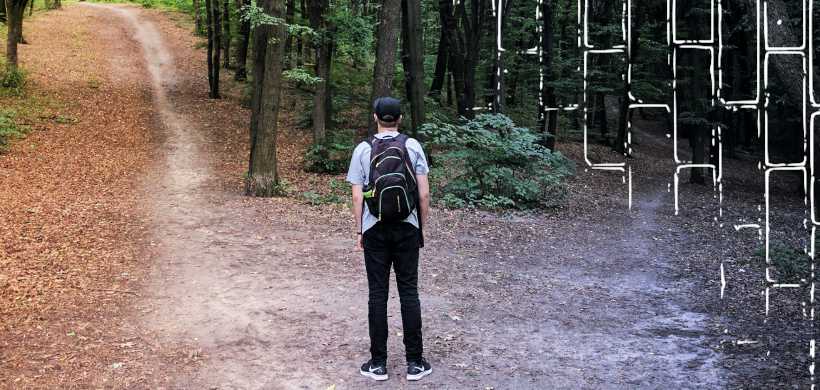 uun hombre que se encuentra en un bosque, está alfrente de dos caminos a escoger