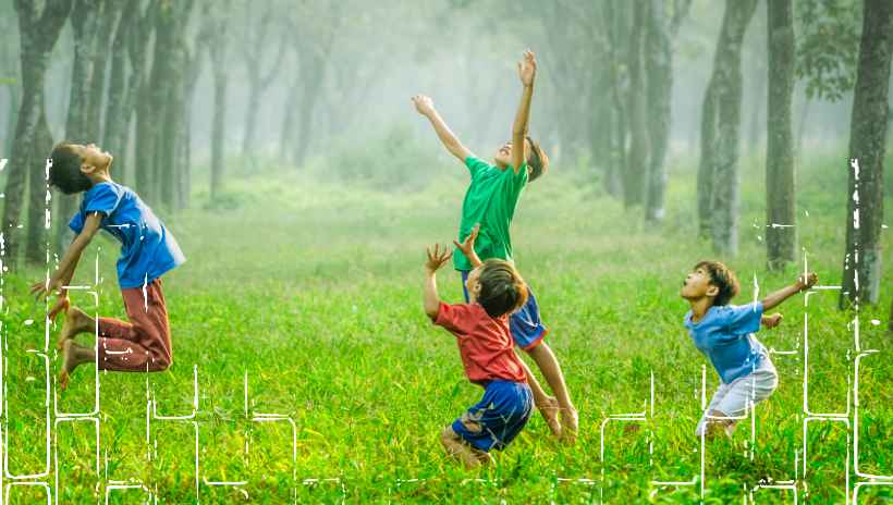cuatro niños brincando en un bosque encima de grama verde
