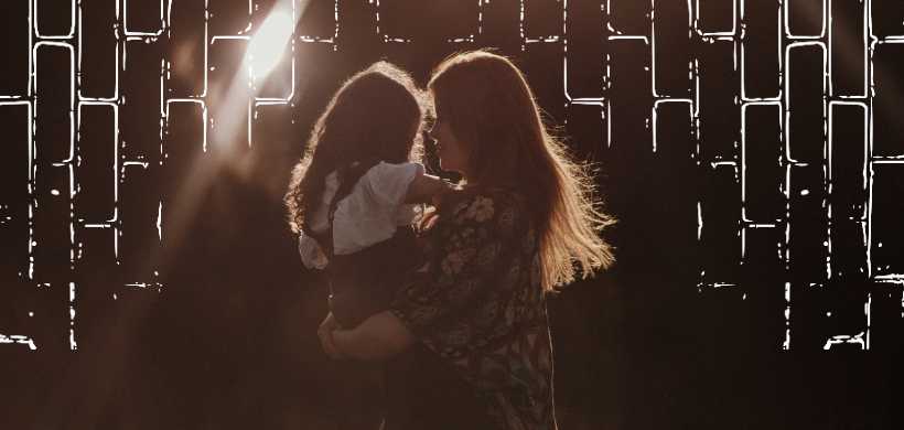 una madre agaundantando a su hija en sus manos, atardecer