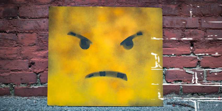 un cuadrado de metal amarrillo con una cara enojada pintada sobre ella