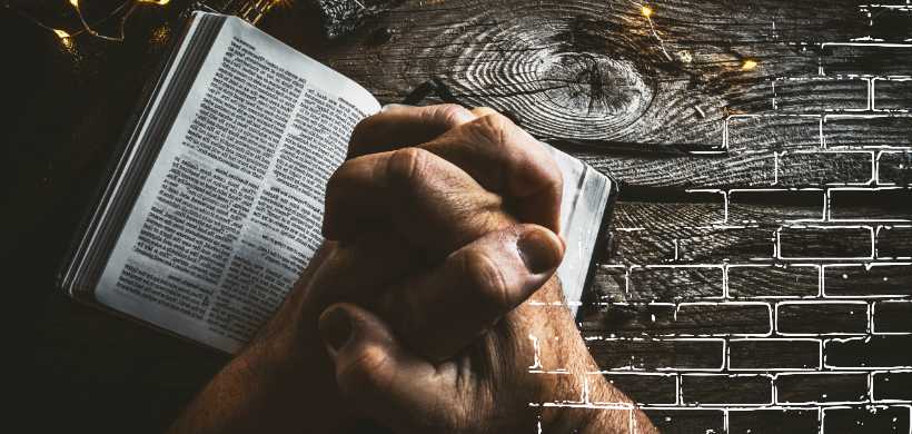manos de un hombre sobre una biblia en forma de oración